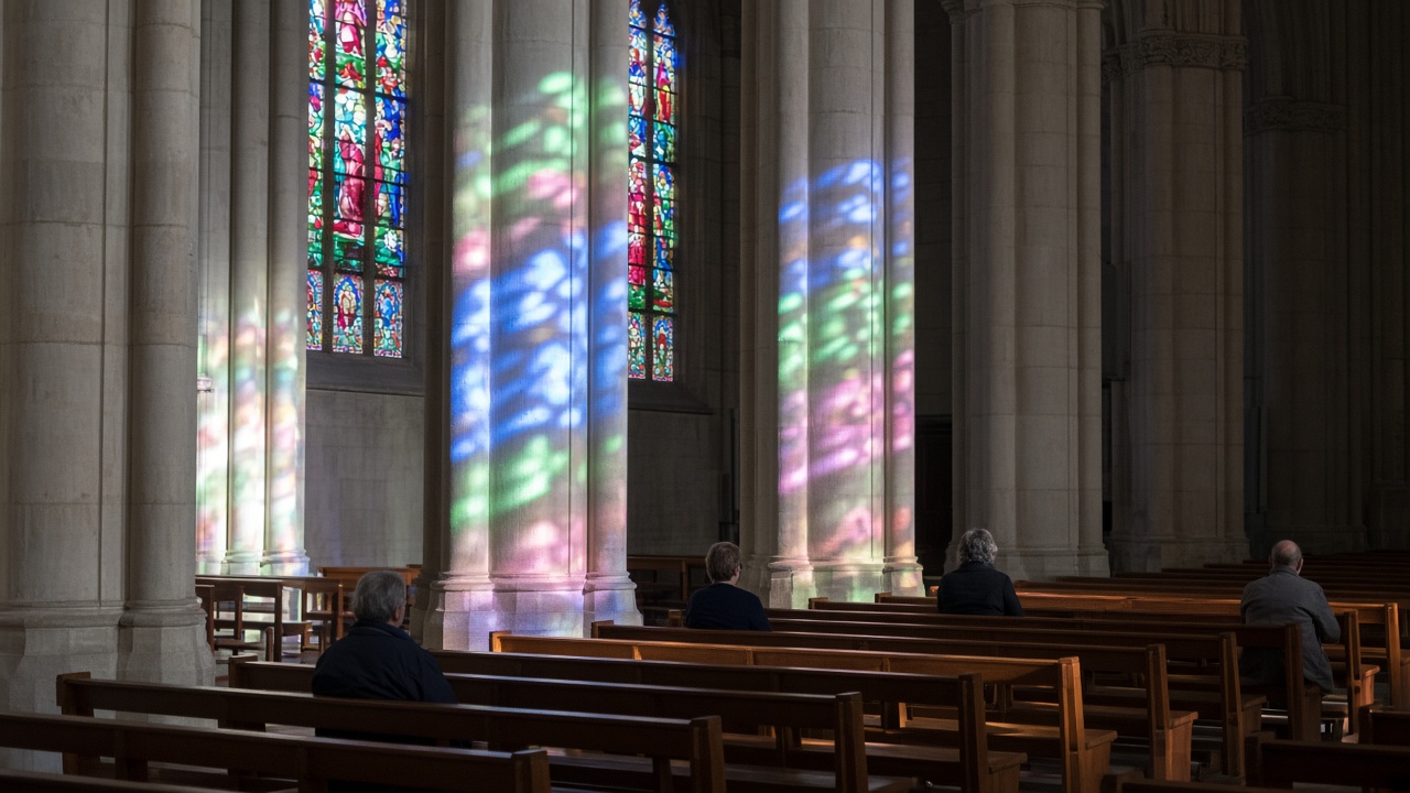 Sunlight through stained glass across the pews of a church